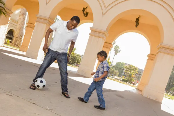 Отец и сын смешанной расы играют в футбол во дворе — стоковое фото
