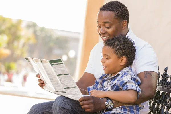 Gemengd ras vader en zoon lezen park brochure buiten — Stockfoto