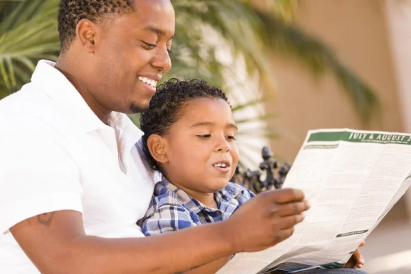 混的血父亲和儿子读外的园宣传册 — 图库照片