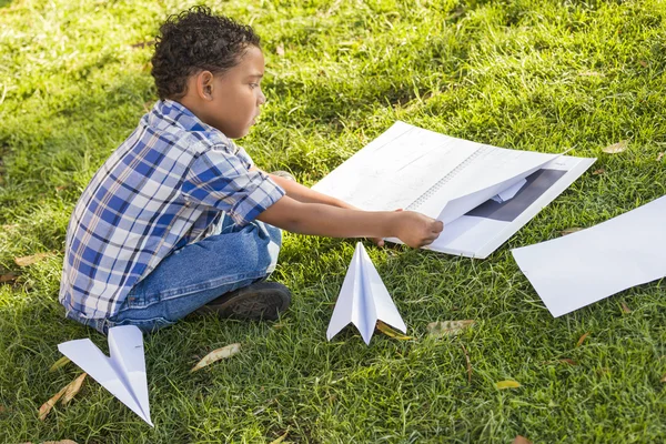Aprendizaje de niño de raza mixta Cómo doblar aviones de papel —  Fotos de Stock