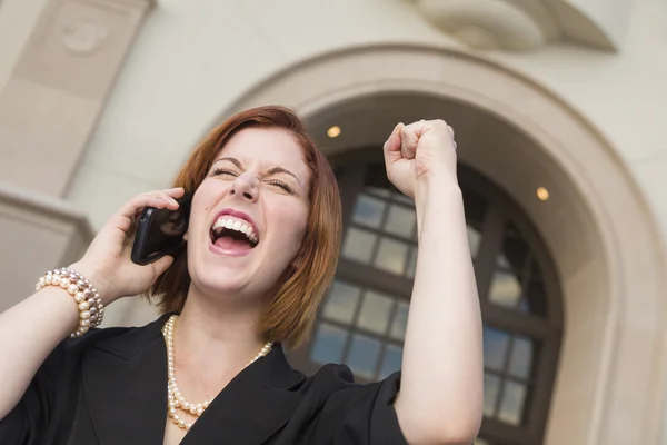 Jonge zakenvrouw met vuist in de lucht op mobiele telefoon — Stockfoto