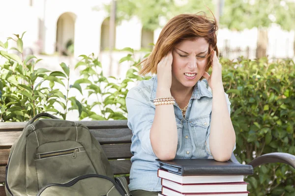 Estudiante femenina afuera con dolor de cabeza sentada con libros y espalda —  Fotos de Stock