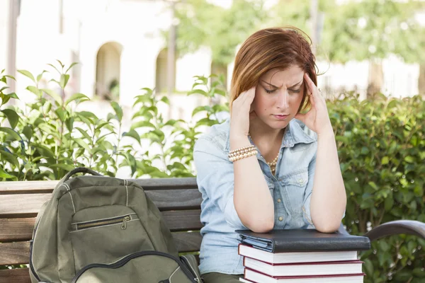 Estudante feminina fora com dor de cabeça sentada com livros e costas — Fotografia de Stock