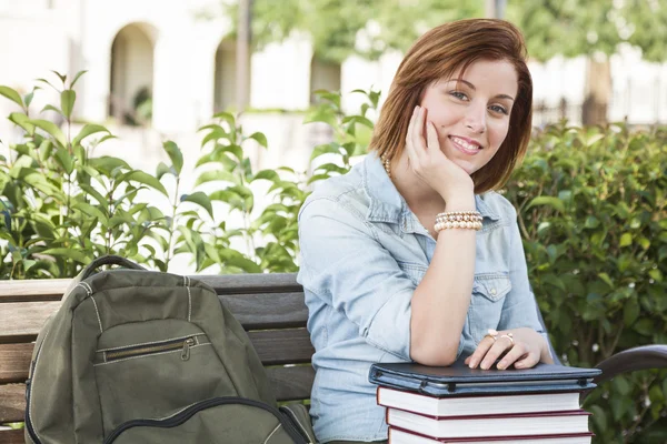 Jovem estudante do sexo feminino sentada no campus com mochila e livros — Fotografia de Stock