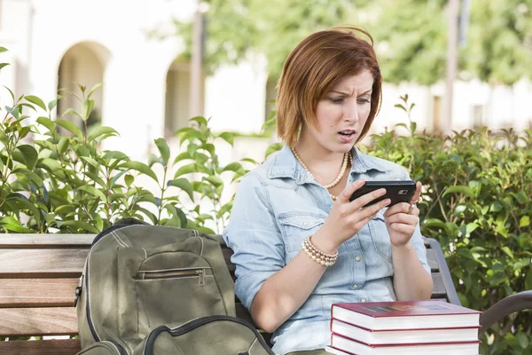 Ошеломленная молодая студентка пишет смс на мобильный телефон — стоковое фото