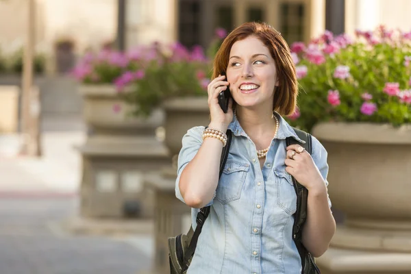 Ung kvinnlig student gå utanför använder mobiltelefon — Stockfoto