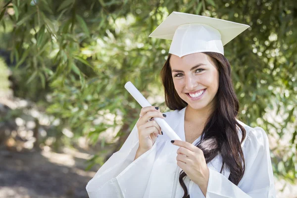 Afstuderen gemengd ras meisje in cap en jurk met diploma — Stockfoto