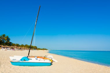 Sailing boats and umbrellas on a beach in Cuba clipart