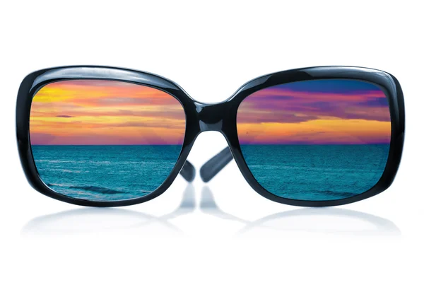 Sonnenbrille, die einen Sonnenuntergang am Meer widerspiegelt — Stockfoto