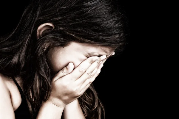 Porträt eines Mädchens, das weint und ihr Gesicht versteckt Stockbild