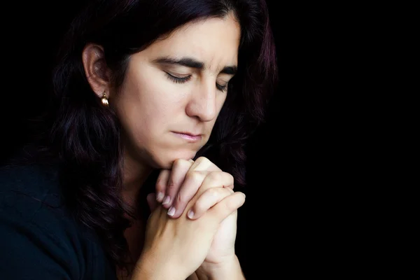 Латиноамериканка, молящаяся изолированно на черном — стоковое фото
