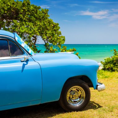 Old american car at a beach in Cuba clipart