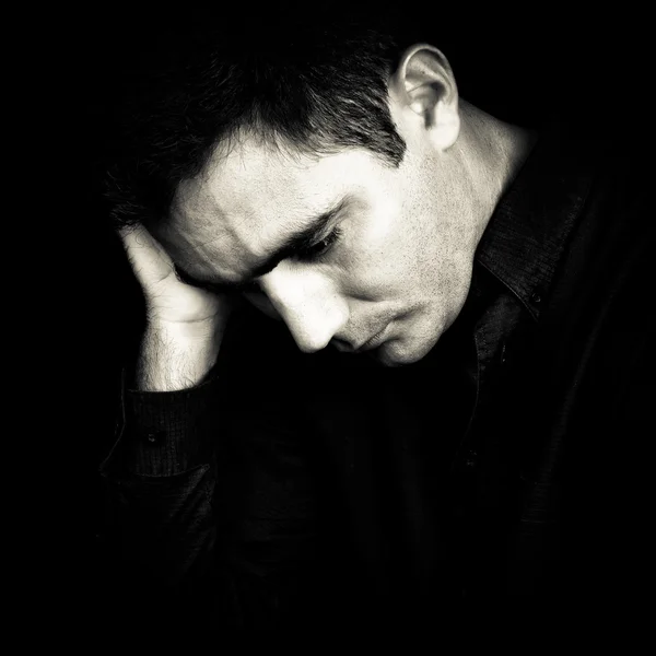 Bezorgd en gedeprimeerd man geïsoleerd op zwart — Stockfoto