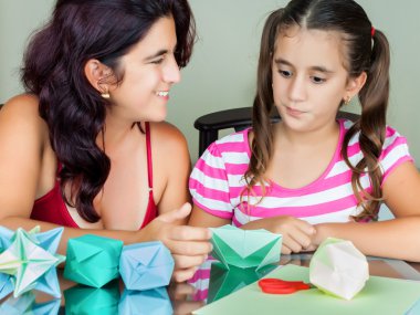 Mother and daughter making origami clipart