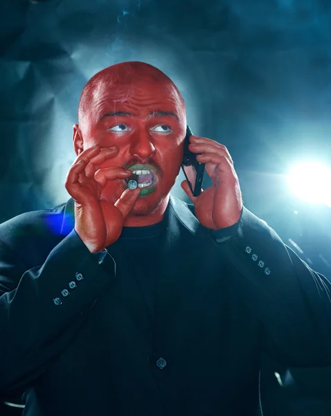Nebezpečný muž s červenou tváří mluví do mobilu. — Stock fotografie