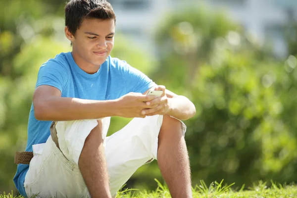 Young male with a mobile in park — Stock Photo, Image