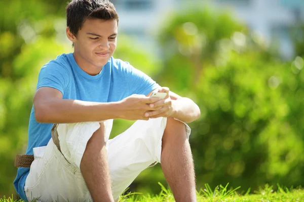 Young male with a mobile in park — Stock Photo, Image