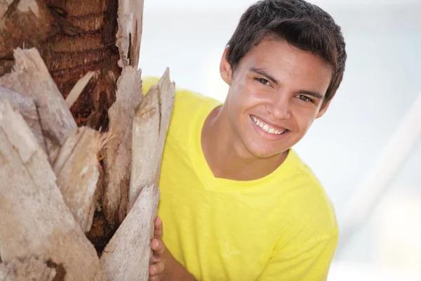 Junger Mann guckt hinter einem Baum hervor — Stockfoto
