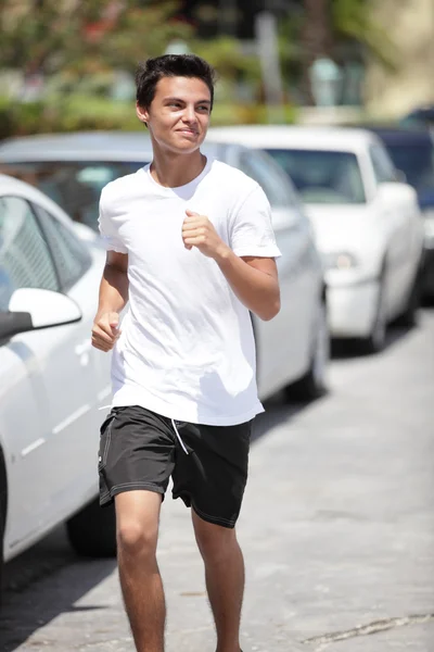 Jovem do sexo masculino correndo rua abaixo — Fotografia de Stock