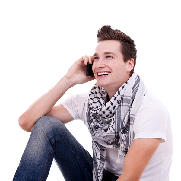Siedzi młody mężczyzna rozmawia przez telefon — Zdjęcie stockowe