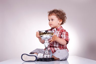 Small boy sitting and holding a trophy