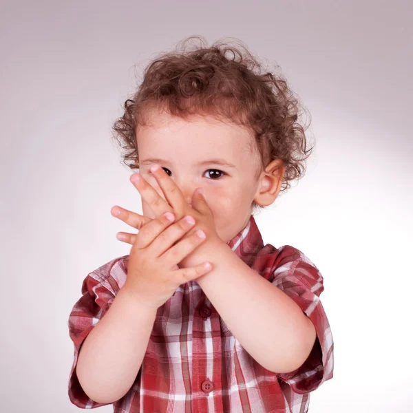 Criança adorável segurando as mãos na frente de seu rosto — Fotografia de Stock
