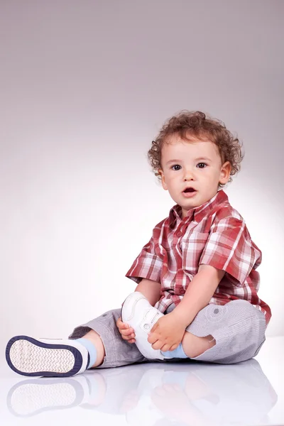 Precious little child sitting and holding his leg — Stock Photo, Image