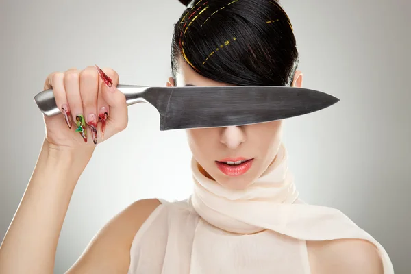 Bella giovane donna si copre gli occhi con un coltello — Foto Stock