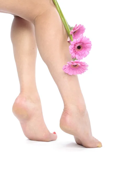 Weibliche Beine und Blumen auf weißem Hintergrund — Stockfoto