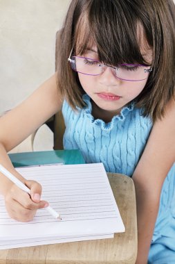 Child Sitting at School Desk With Glasses clipart