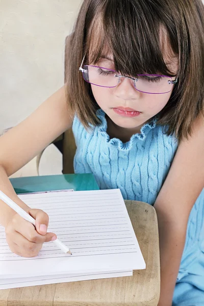 Ребенок сидит за школьным столом в очках — стоковое фото