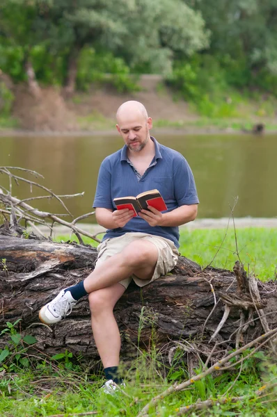 Счастливый лысый человек, читающий книгу на природе — стоковое фото