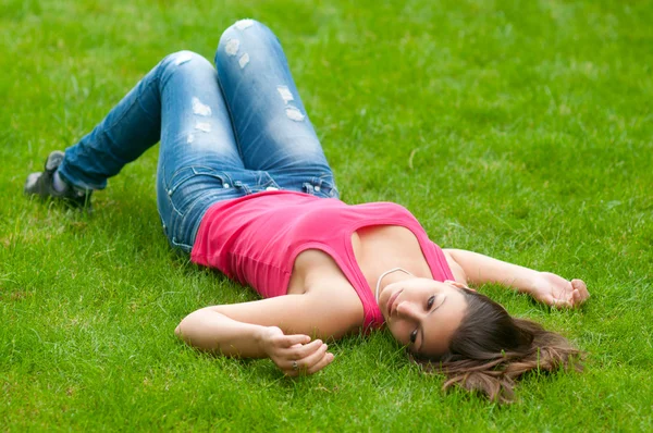 美丽的女孩躺在草地上，平静的春天天 — 图库照片