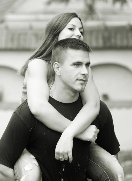 Young happy couple piggy back riding outdoor - monochrome photo — Stock Photo, Image