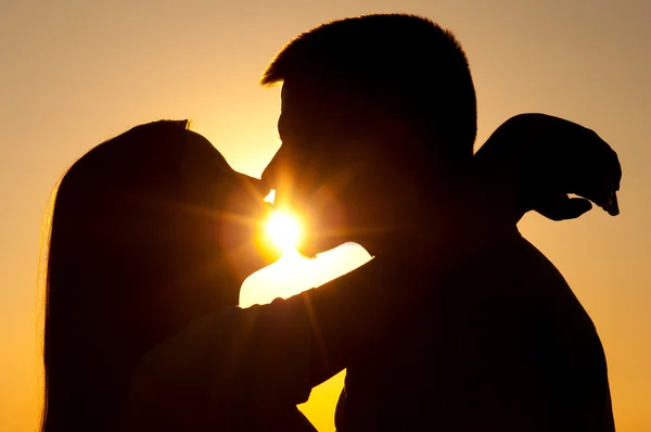Sylwetki młoda para całuje w słoneczny letni dzień — Zdjęcie stockowe