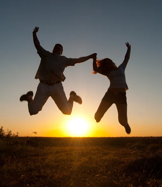 Młoda szczęśliwa para wysokie skoki w powietrzu w słoneczny letni dzień — Zdjęcie stockowe