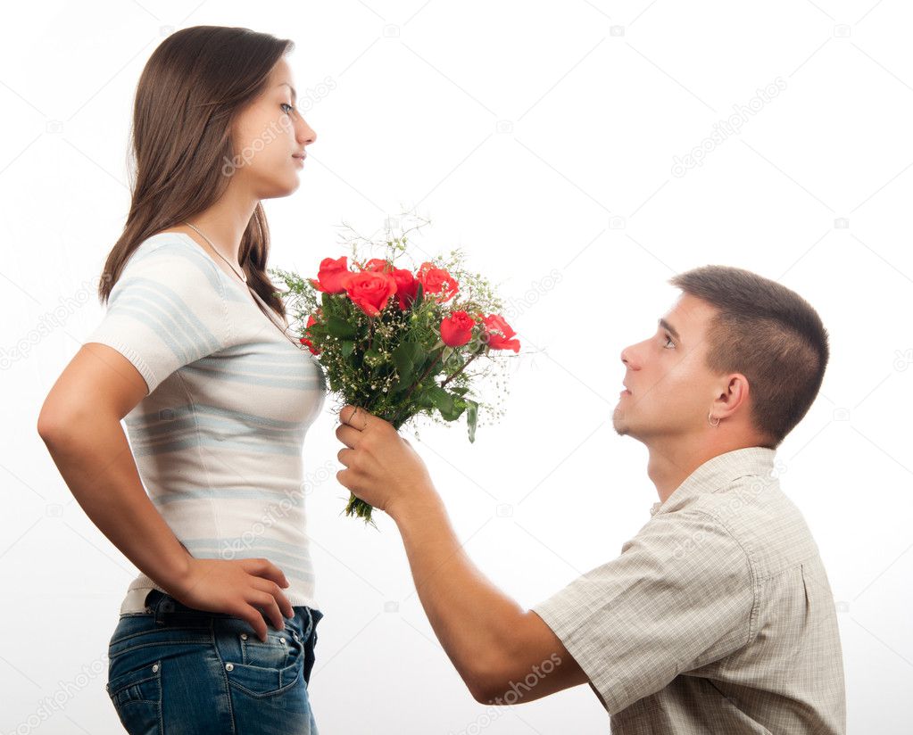 Handsome young man pleading for forgiveness and offering bouquet of roses to his girlfriend