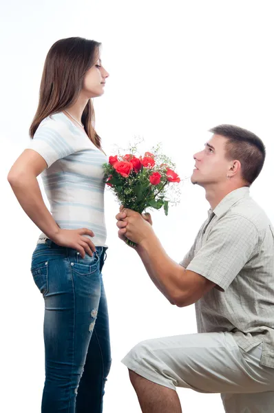Schöner junger Mann fleht um Vergebung und bietet seiner Freundin einen Strauß Rosen an — Stockfoto