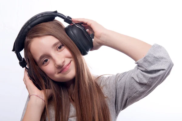 Beautiful teenage girl listens to music through the headphones — Stock Photo, Image