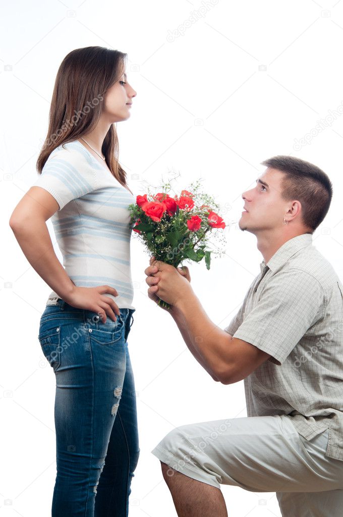 Handsome young man pleading for forgiveness and offering bouquet of roses to his girlfriend