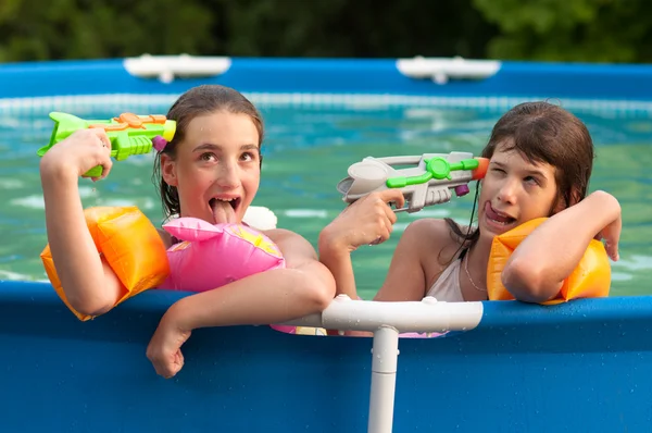 Two teenage girls having fun with their childhood toys in the home pool — Stock Photo, Image