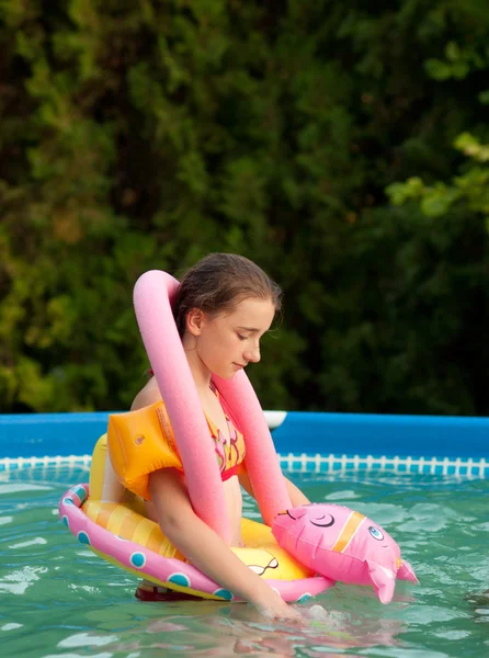 Trauriges Teenagermädchen, das allein mit ihrem Kinderspielzeug im Pool spielt — Stockfoto