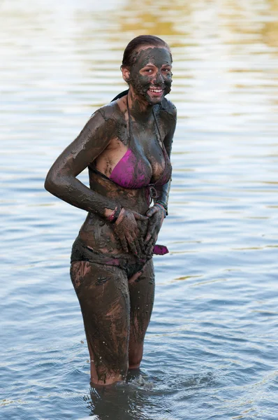 Glad tonårig flicka stående i floden täckt med lera — Stockfoto