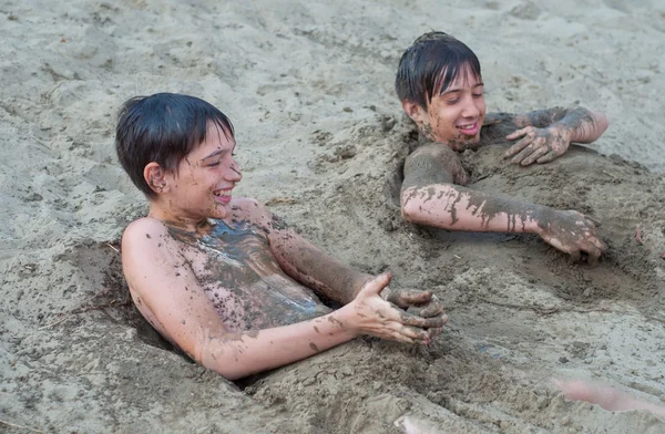 Cute happy teenage boys playing in the sand — Stock Photo, Image