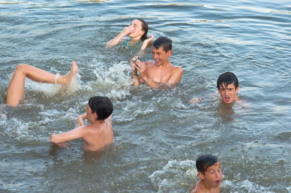 Tiener jongens en meisjes plezier in het water op een mooie zomerdag — Stockfoto