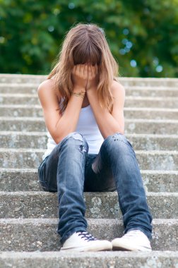 Yalnız merdivenlerde oturan üzgün genç kız