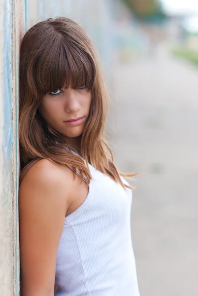 Beautiful teenage girl leaning against concrete wall — Stock Photo, Image