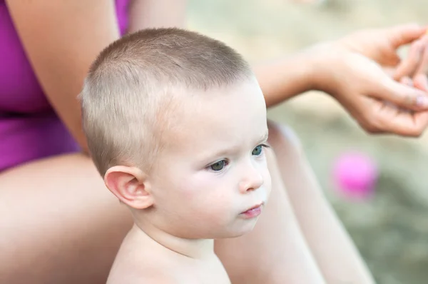 ビーチで彼の母親の隣に座ってかわいい男の子 — ストック写真