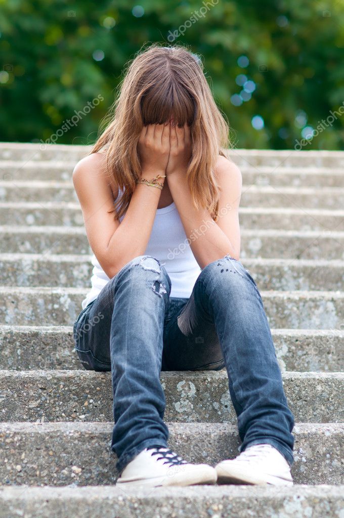 Sad teenage girl sitting alone on the stairs — Stock Photo © prudkov ...