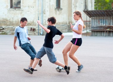 Teenage boys and girls playing soccer on the playground clipart